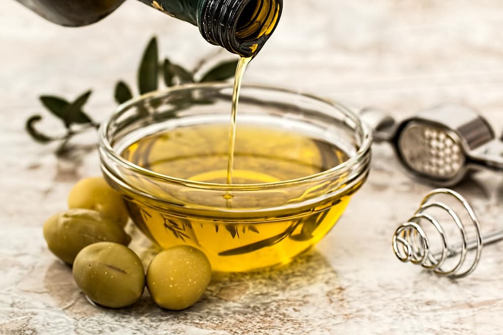 bottiglia di olio d'oliva che viene versata in una ciotola