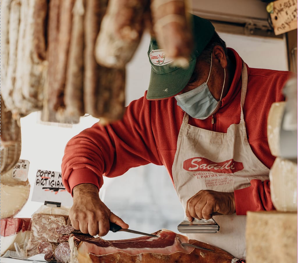venditore che taglia il prosciutto artigianale in una gastronomia