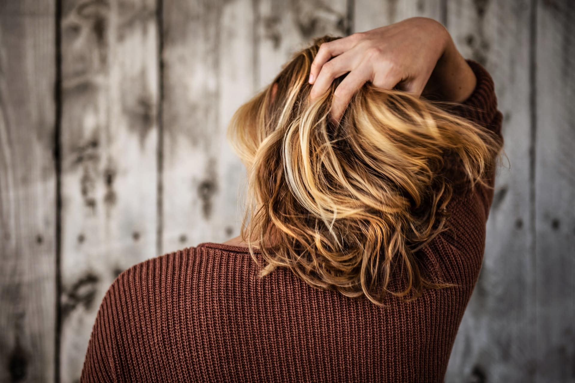 donna di spalle che si passa una mano tra i capelli